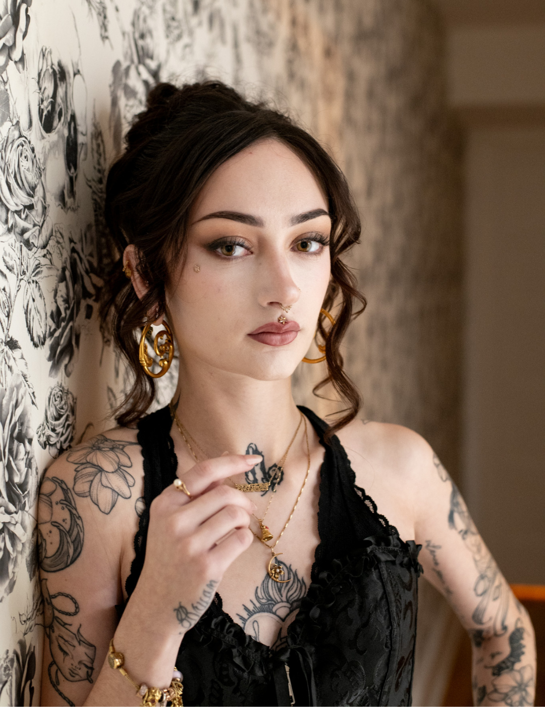 Portrait of Alayna from the Guest Happiness Team posing against floral wallpaper with a dark updo.