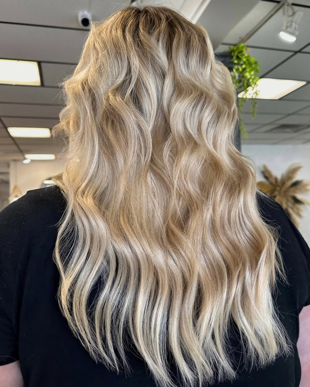 Back view of long blonde wavy hair featuring 3 rows of Bellami volume wefts by stylist Julia in New Orleans, Louisiana.