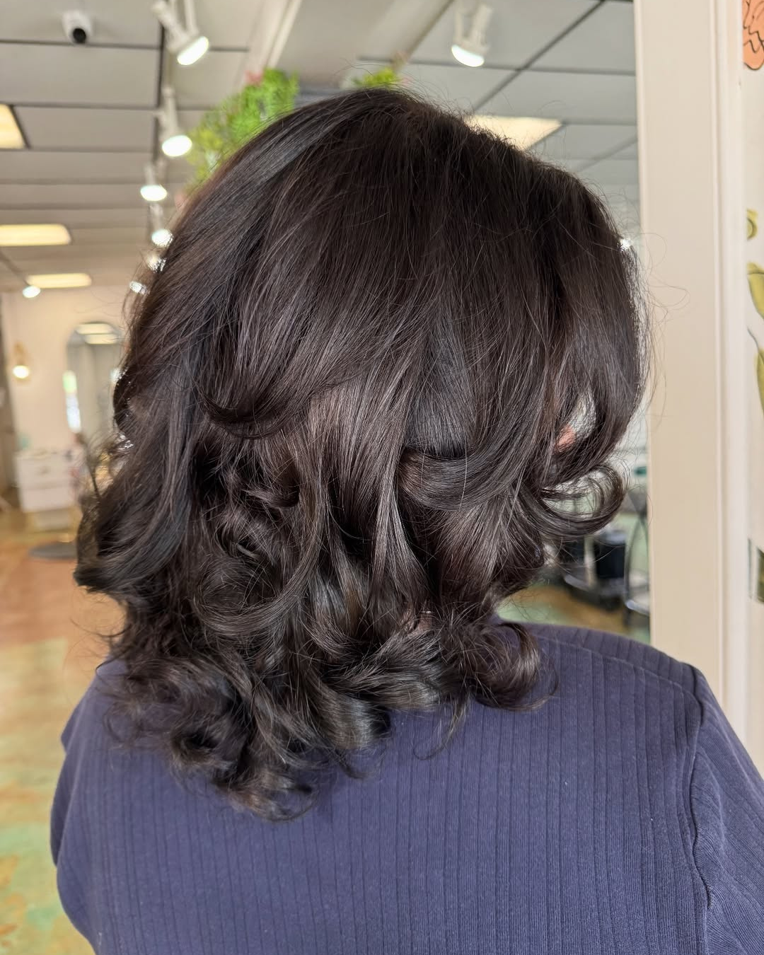 Short dark brunette hair styled in a layered bouncy blowout with face-framing curls by Marie.