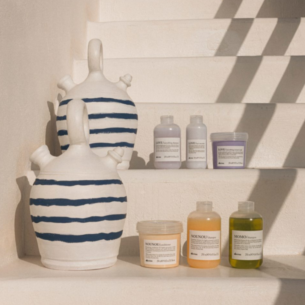 Davines Essential Haircare products including Love, Nounou, and Momo lines on white stairs.