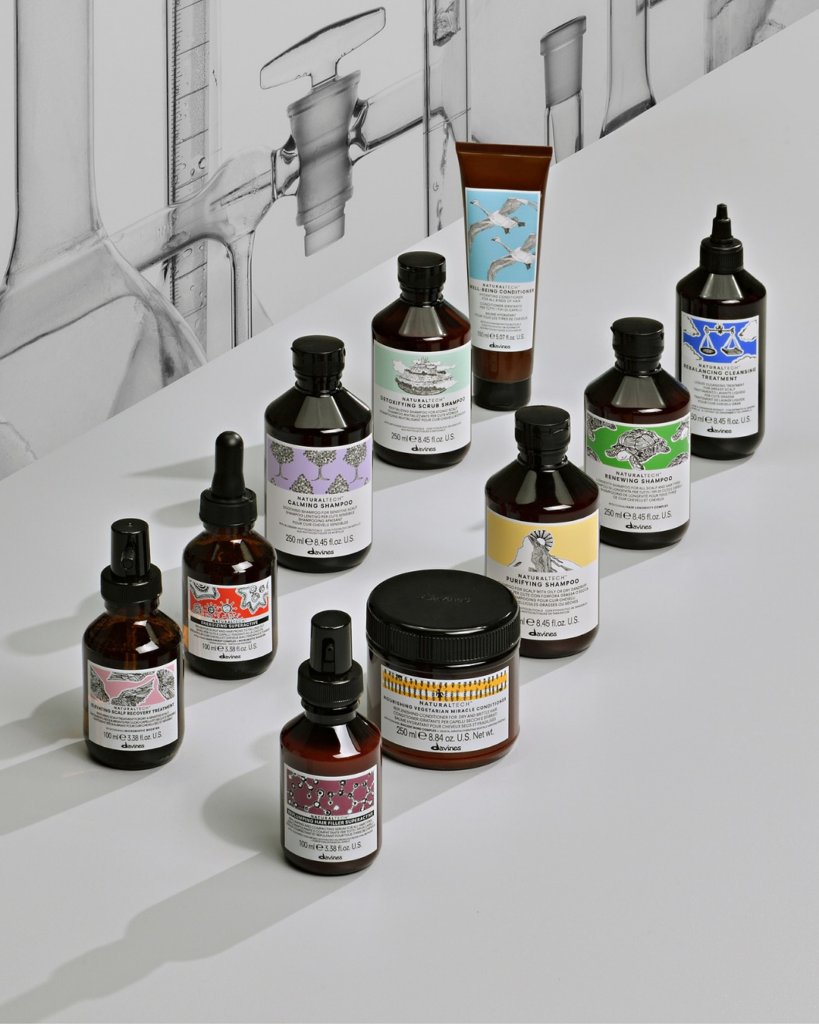 A collection of Davines Naturaltech hair care products, including shampoos, treatments, and conditioners in amber glass bottles with artistic labels.