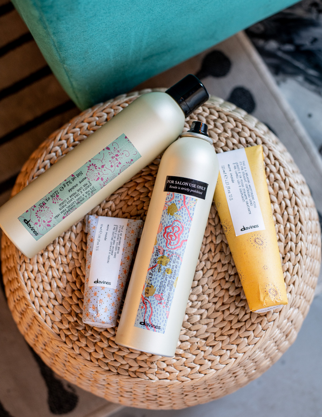 Assorted Davines hair care products, including hairspray and creams, displayed on a woven wicker stool in Traci Woodard Salon in Louisiana.