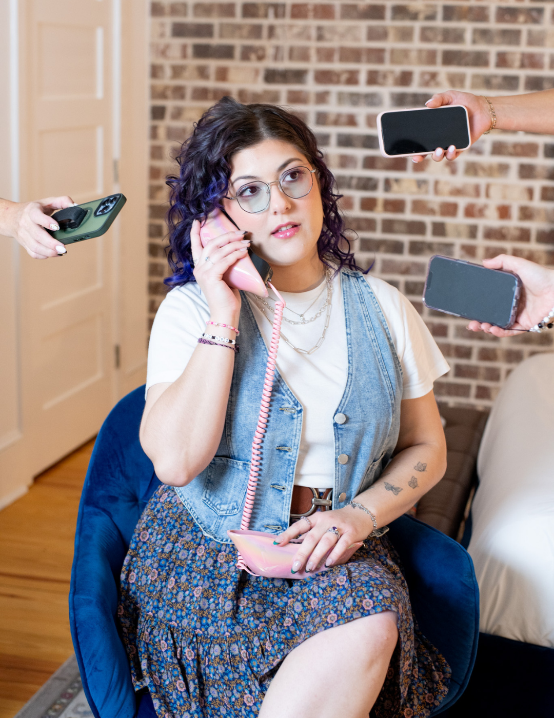 A member of the salon guest happiness team answering a pink rotary phone while surrounded by modern smartphones.
