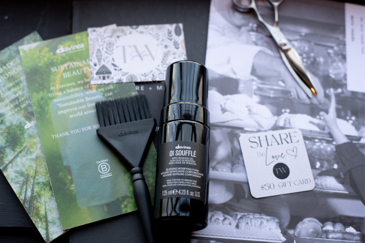 Professional hair styling tools including shears, a color brush, and Davines Oi Souffle product next to a "Share the Love" gift card in New Orleans, Louisiana.