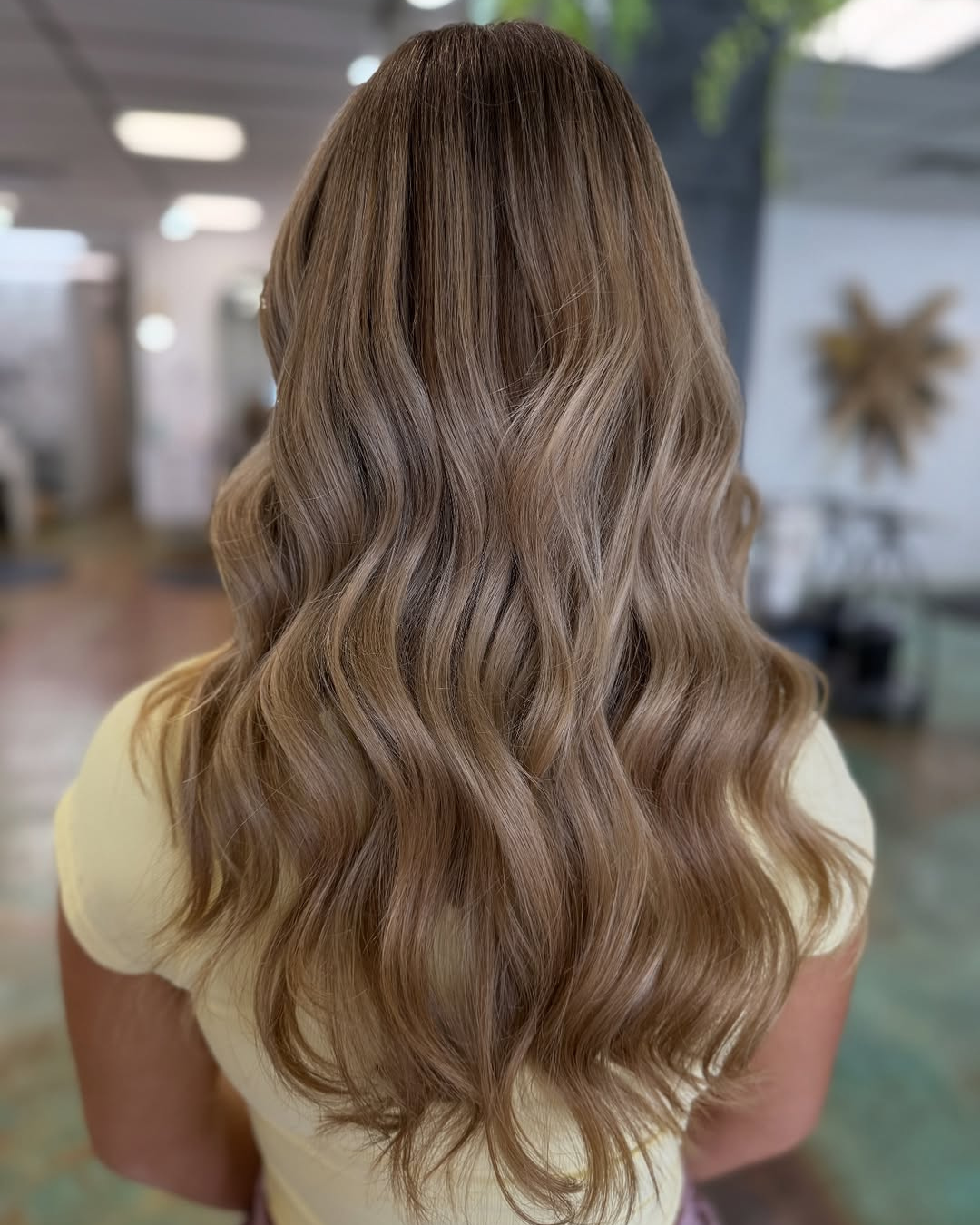 Long hair featuring a dimensional lived-in blonde balayage styled with soft, glamorous waves, styled by Marie.