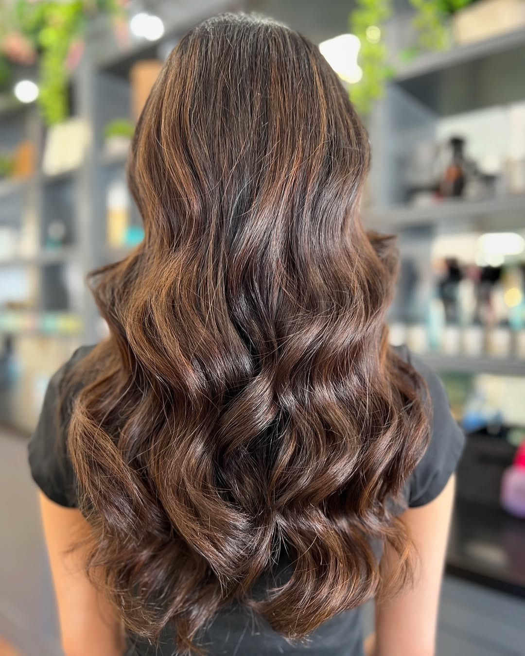 Rear view of long, dark brunette hair with subtle, natural-looking warm brown highlights and wavy texture, styled by Marie.